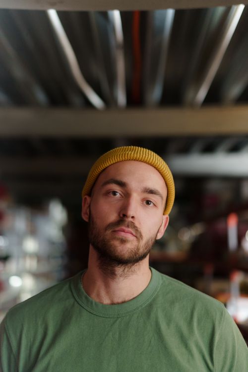 Free Casual portrait of a bearded man wearing a green shirt and yellow beanie indoors. Stock Photo