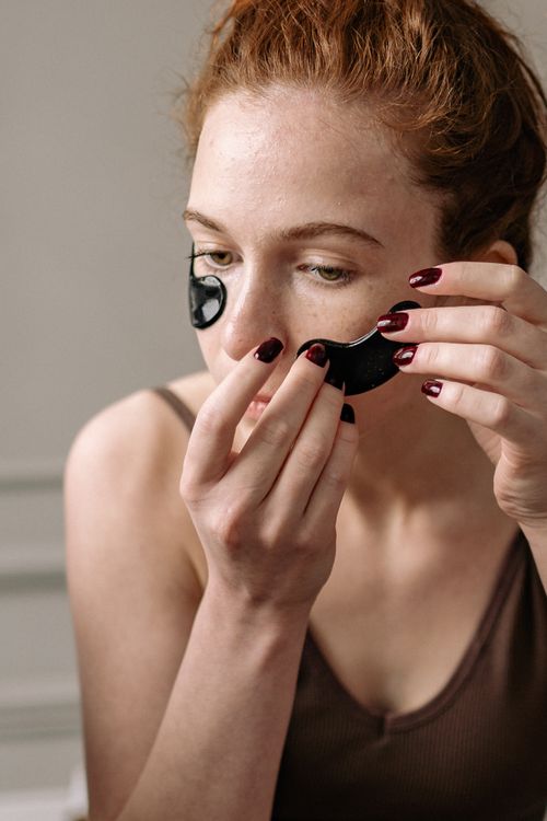 Free Close-up of a woman applying under eye patches as part of her skincare routine. Stock Photo