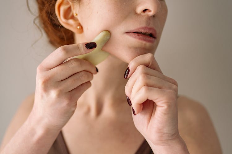 Photograph Of A Woman Using A Jade Stone On Her Face