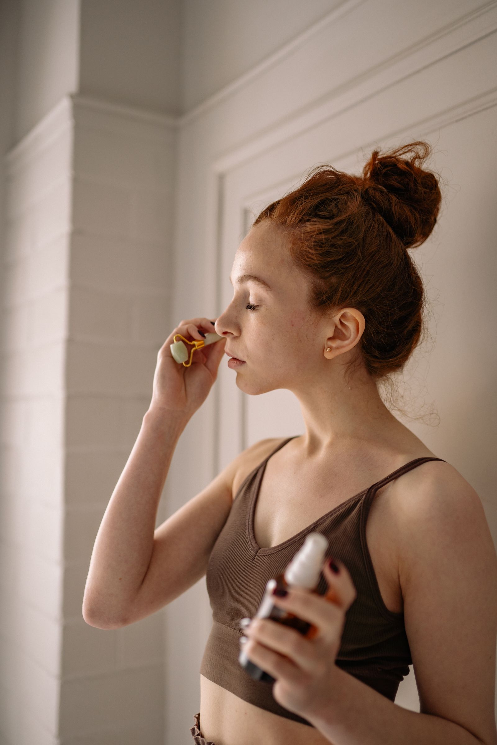 Woman incorporating a facial roller into an at-home self-care routine