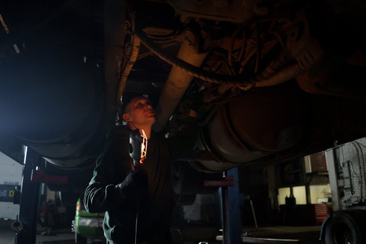 A Man Holding A Light Checking Under A Vehicle