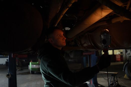 A Man Holding a light Checking the Underbody of a Vehicle
