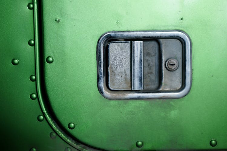 A Stainless Door Handle With A Keyhole On A Green Door