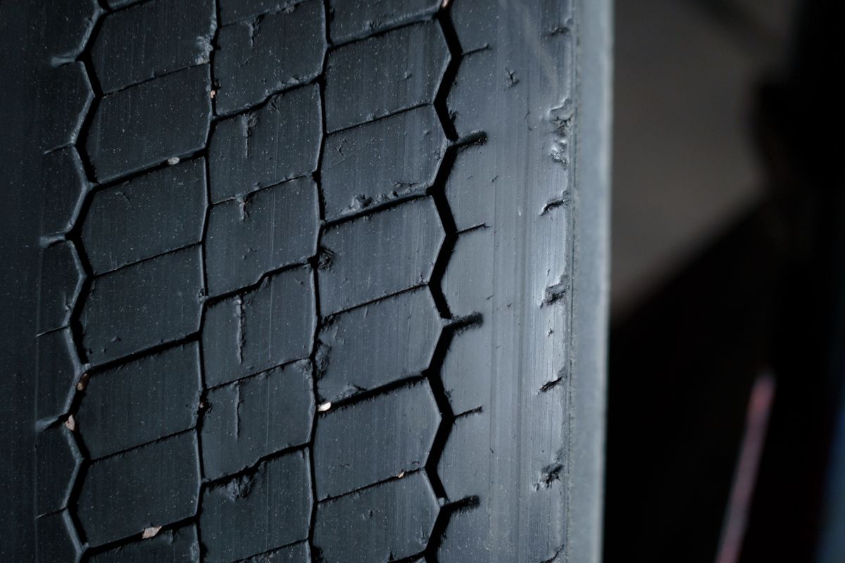 Close-up of a heavy-duty tire tread showing wear, cracking, and embedded debris that can lead to a blowout