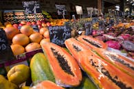 户外市场的摊位上，摆满了木瓜等新鲜水果，充满活力