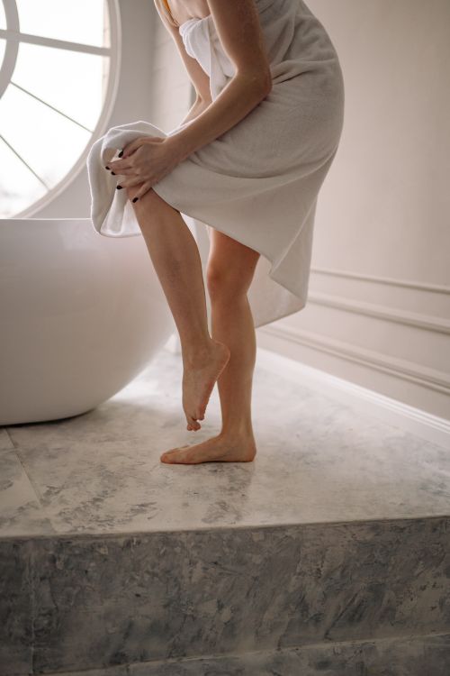 Free A woman wrapped in a white towel stepping out of a luxurious bathroom. Stock Photo