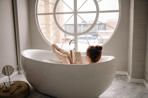 Woman Reading a Book While in a Bathtub