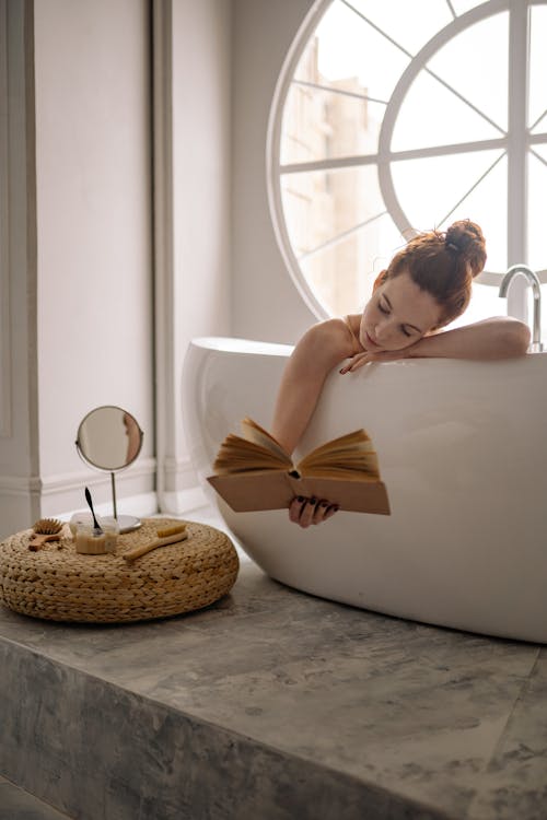 Free Woman in Bathtub Reading a Book Stock Photo