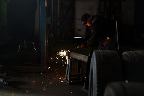 Free Photograph of a Man Welding Near Tires Stock Photo