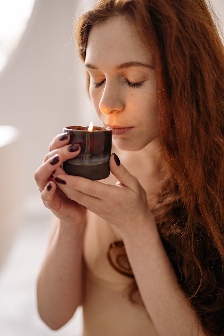 Woman Smelling A Candle