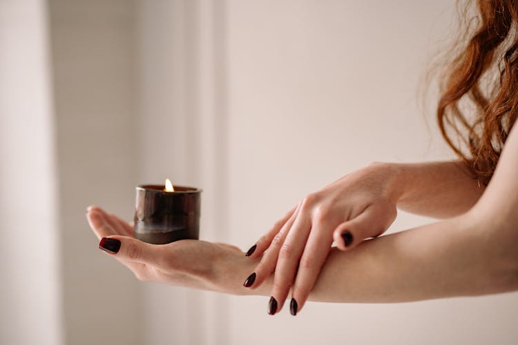 A Person Holding A Candle In A Glass Jar