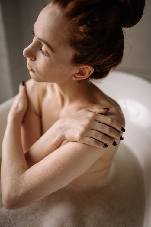 Free Photo of a Woman in a Bathtub with Her Hands on Her Shoulders Stock Photo