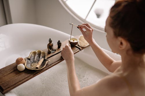 Person Holding Brown Stick while inside the Bathtub
