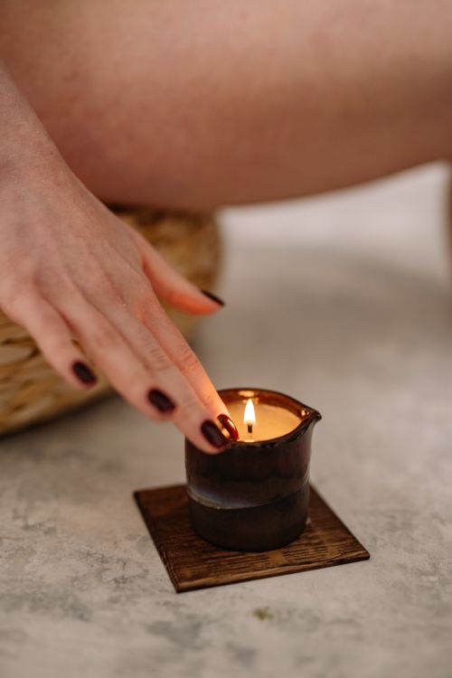 Free Hand with dark nail polish touching burning candle in serene setting, promoting relaxation. Stock Photo