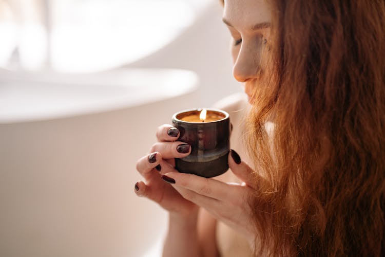 A Woman Smelling A Candle