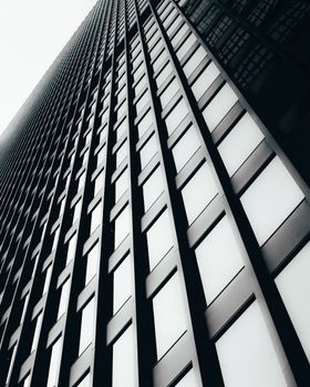 A low-angle view of a modern skyscraper's geometric facade in black and white.