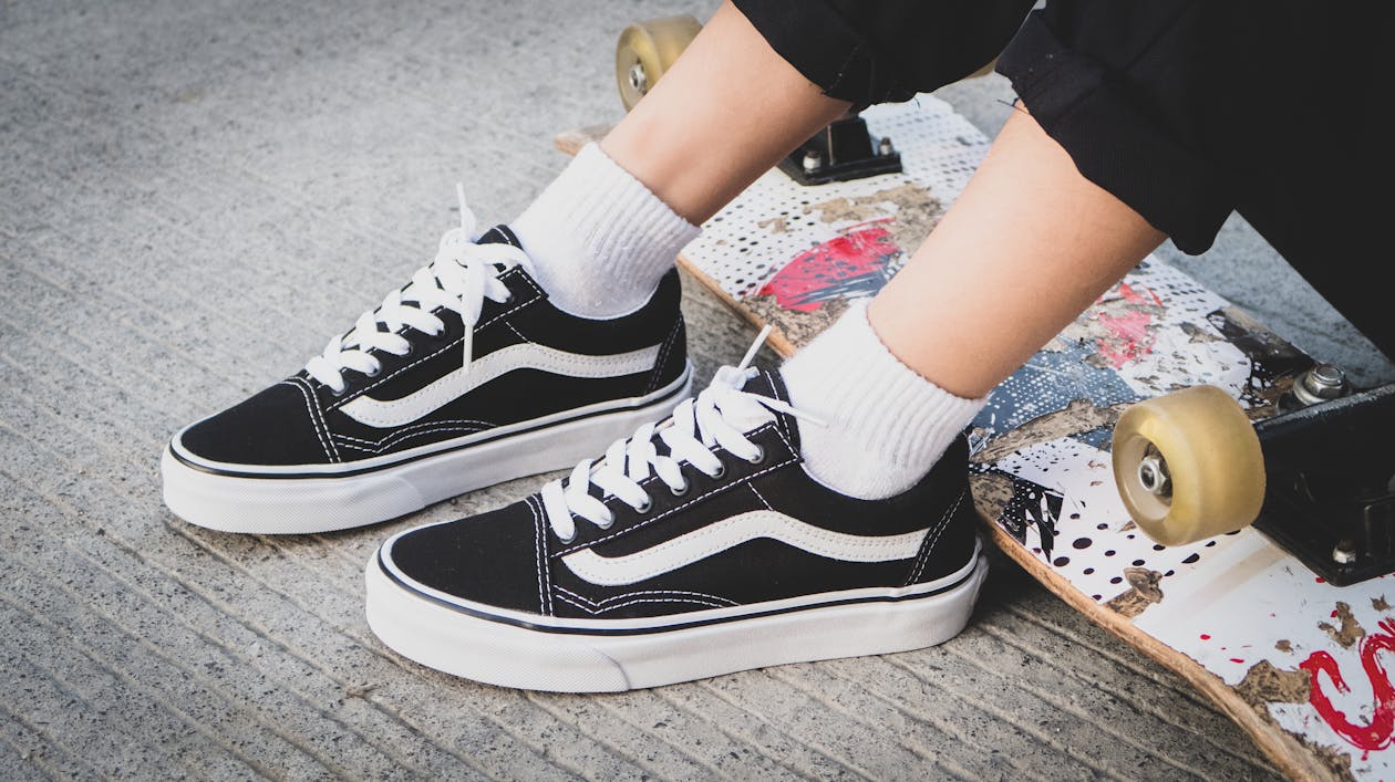 Close-Up Photo of a Person Wearing Black and White Sneakers