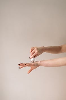 Close-up of woman applying moisturizing cream on arm for skincare routine.