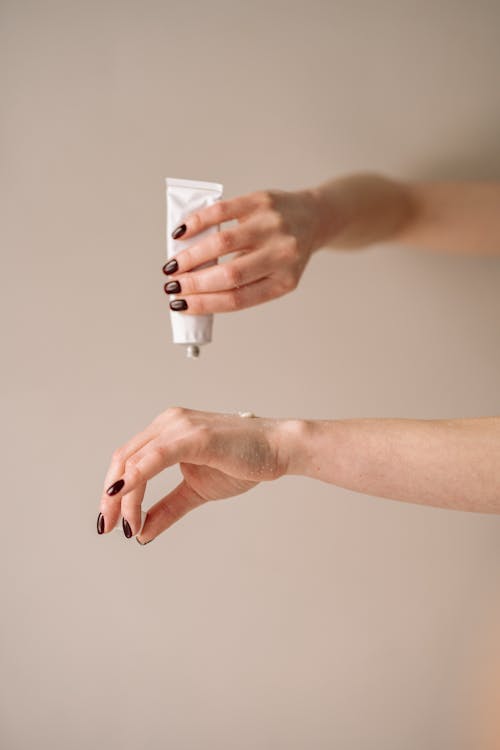 Free Photo of a Person's Hands Applying Lotion on Her Hand Stock Photo