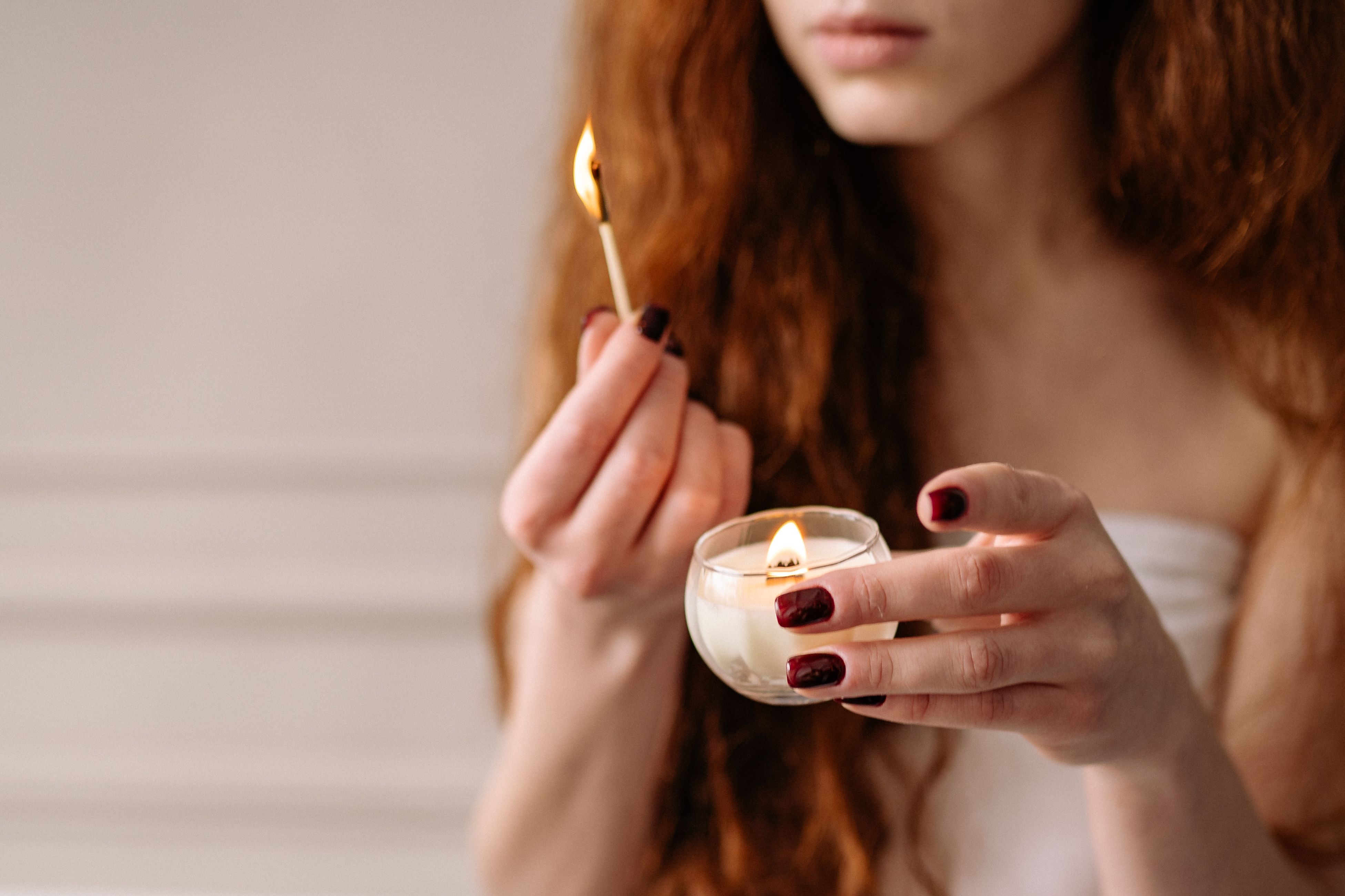 A serene moment of a woman lighting a candle, emphasizing relaxation and calm.