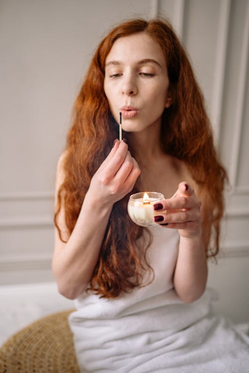 Free Photo of a Woman with Red Hair Blowing a Matchstick Stock Photo