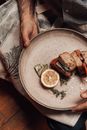 High angle of crop unrecognizable male holding plate with delicious starters with salmon between bread pieces with seasonings