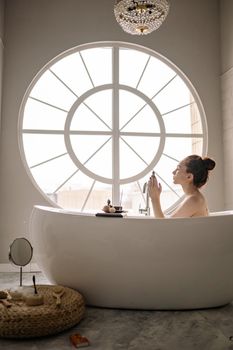 Serene scene of a woman enjoying a relaxing bath by a large window, promoting self-care and tranquility.