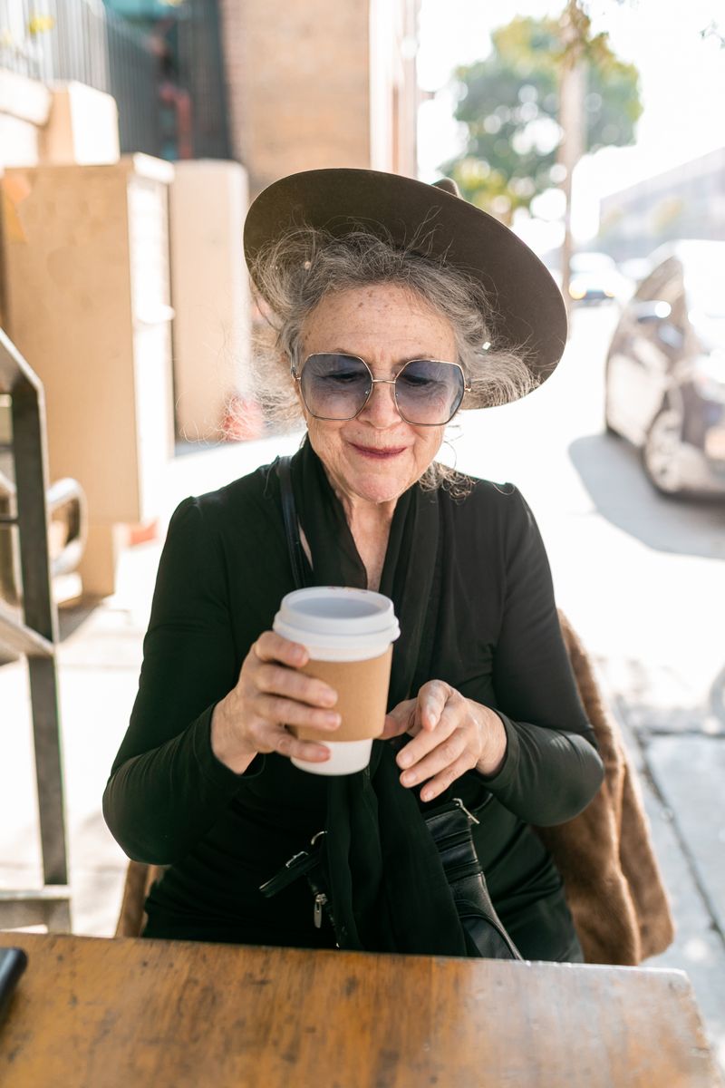 Elegant woman in black holding a coffee cup outdoors
