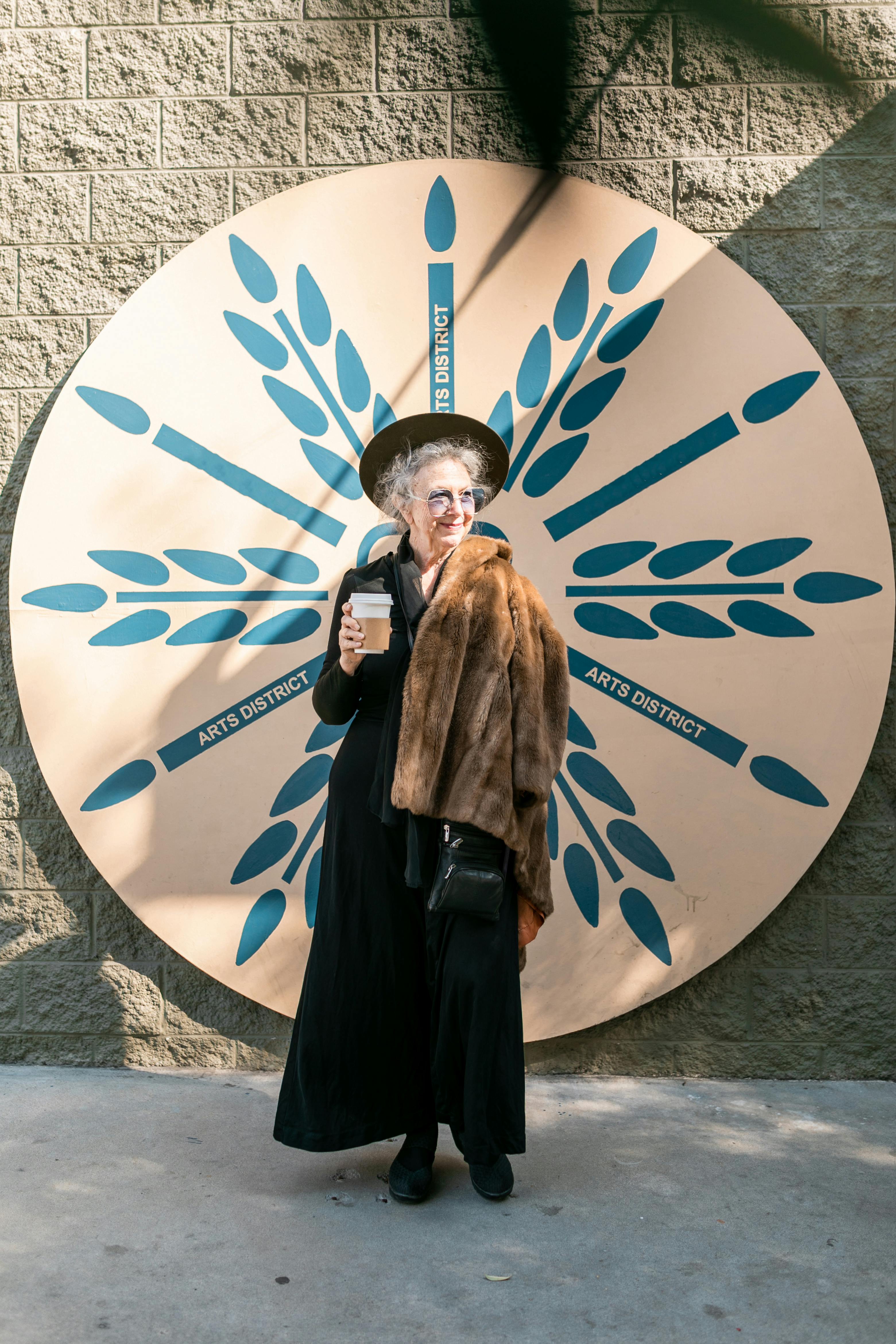 elderly woman in black standing beside white and blue round wall decor