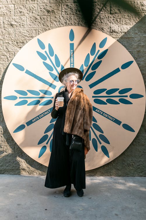 Free Elderly Woman in Black Standing Beside White and Blue Round Wall Decor Stock Photo