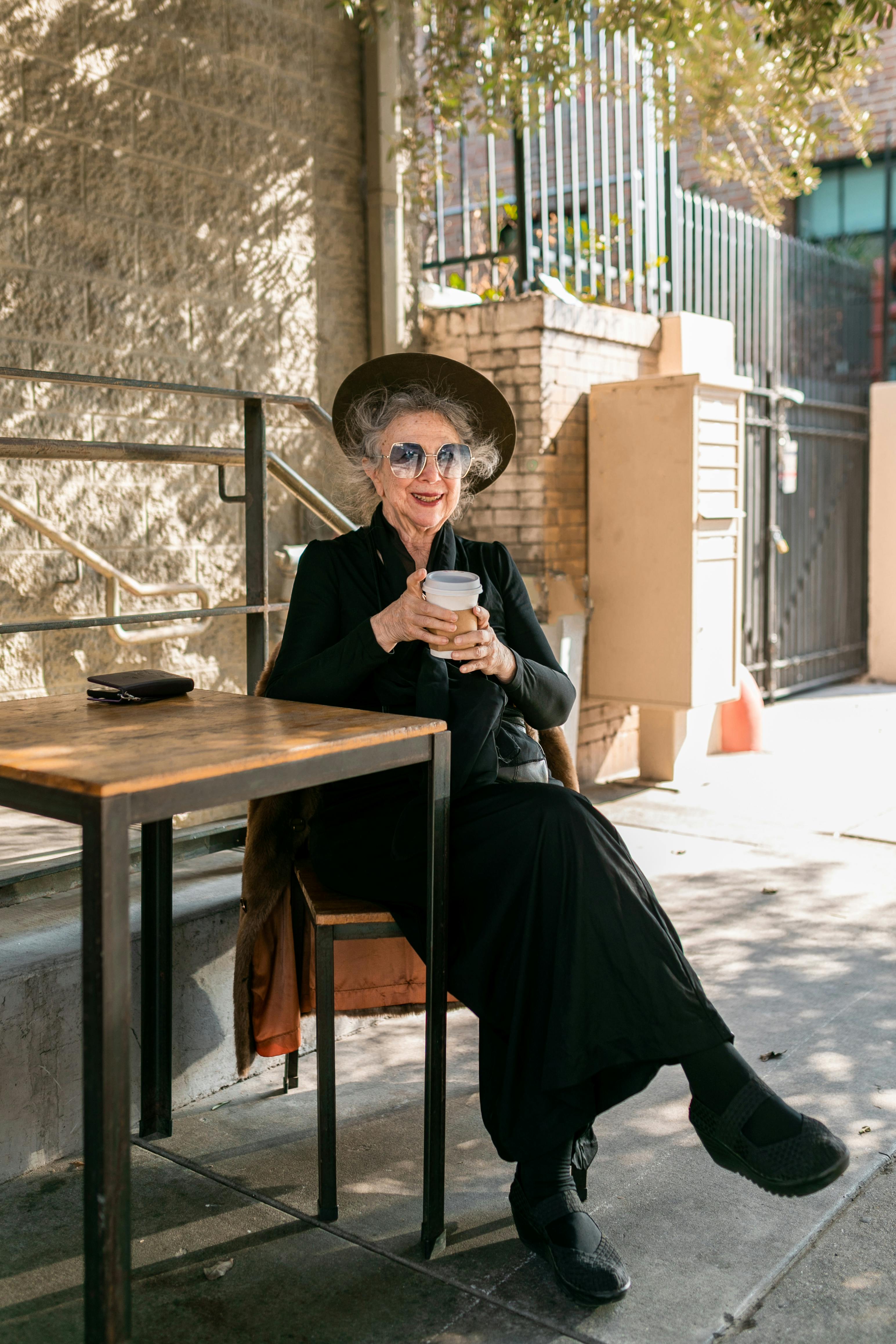 elderly woman sitting beside a table having coffee