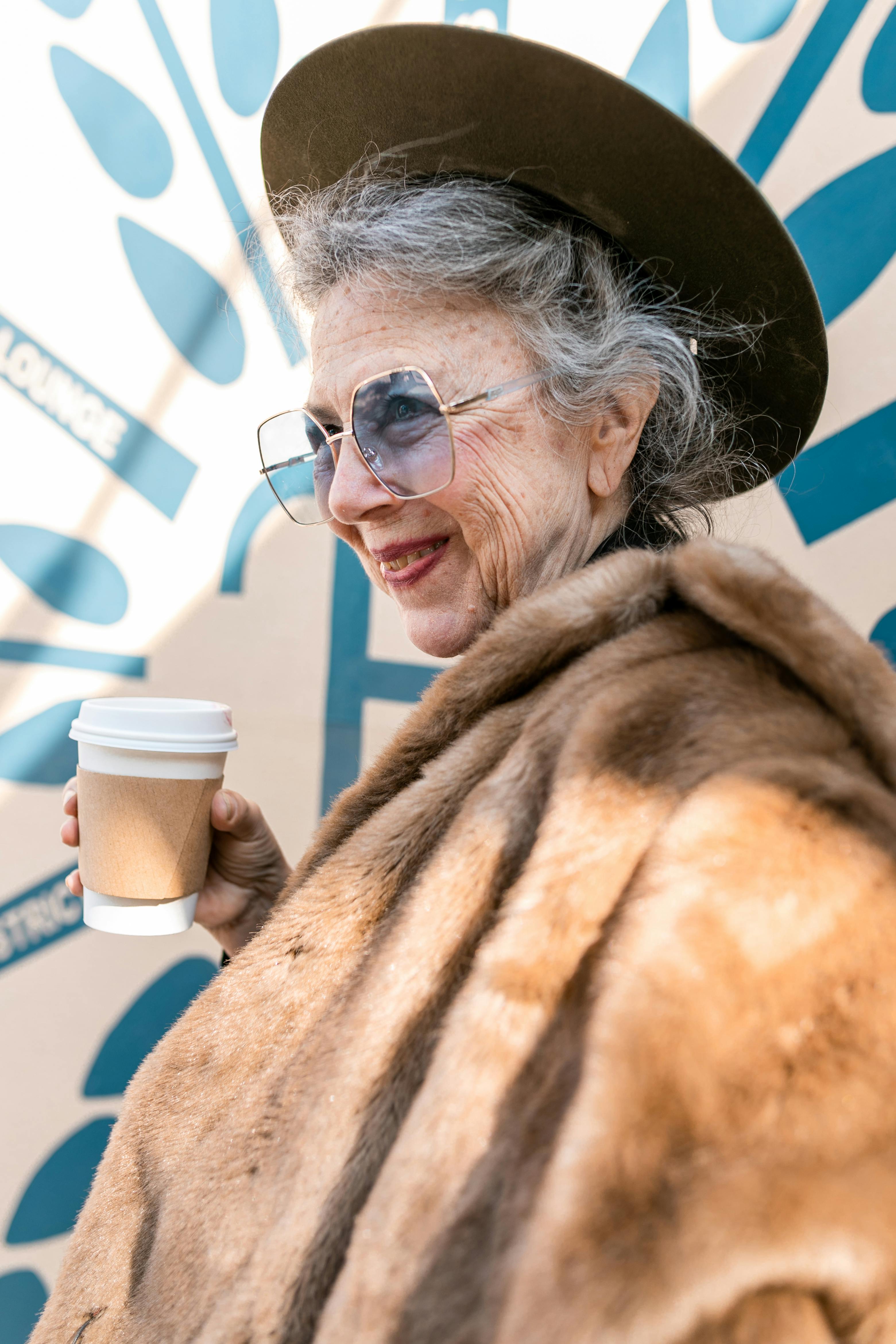 woman in brown fur coat holding white disposable cup