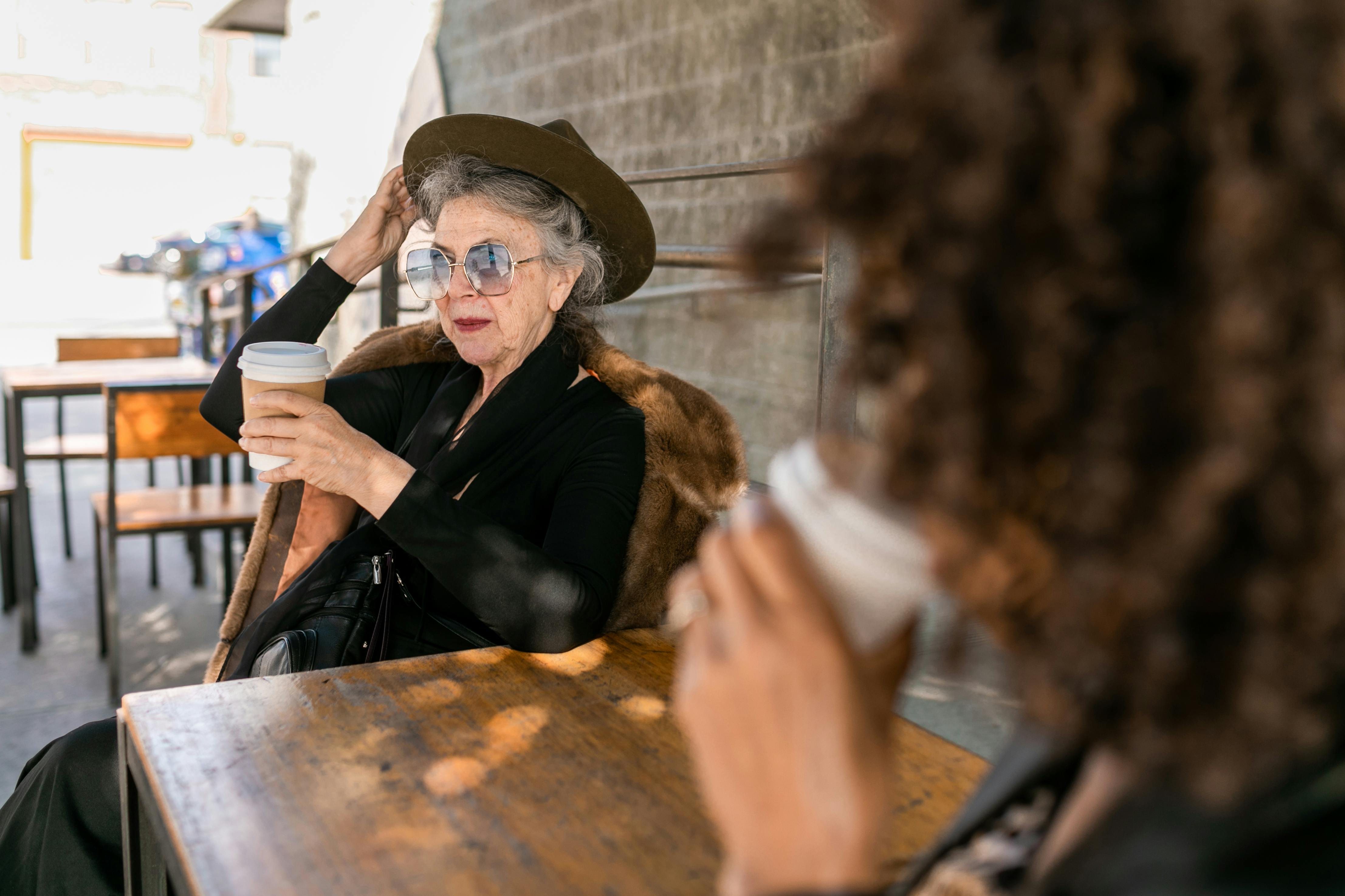 woman in black long sleeve shirt sitting on chair with coffee