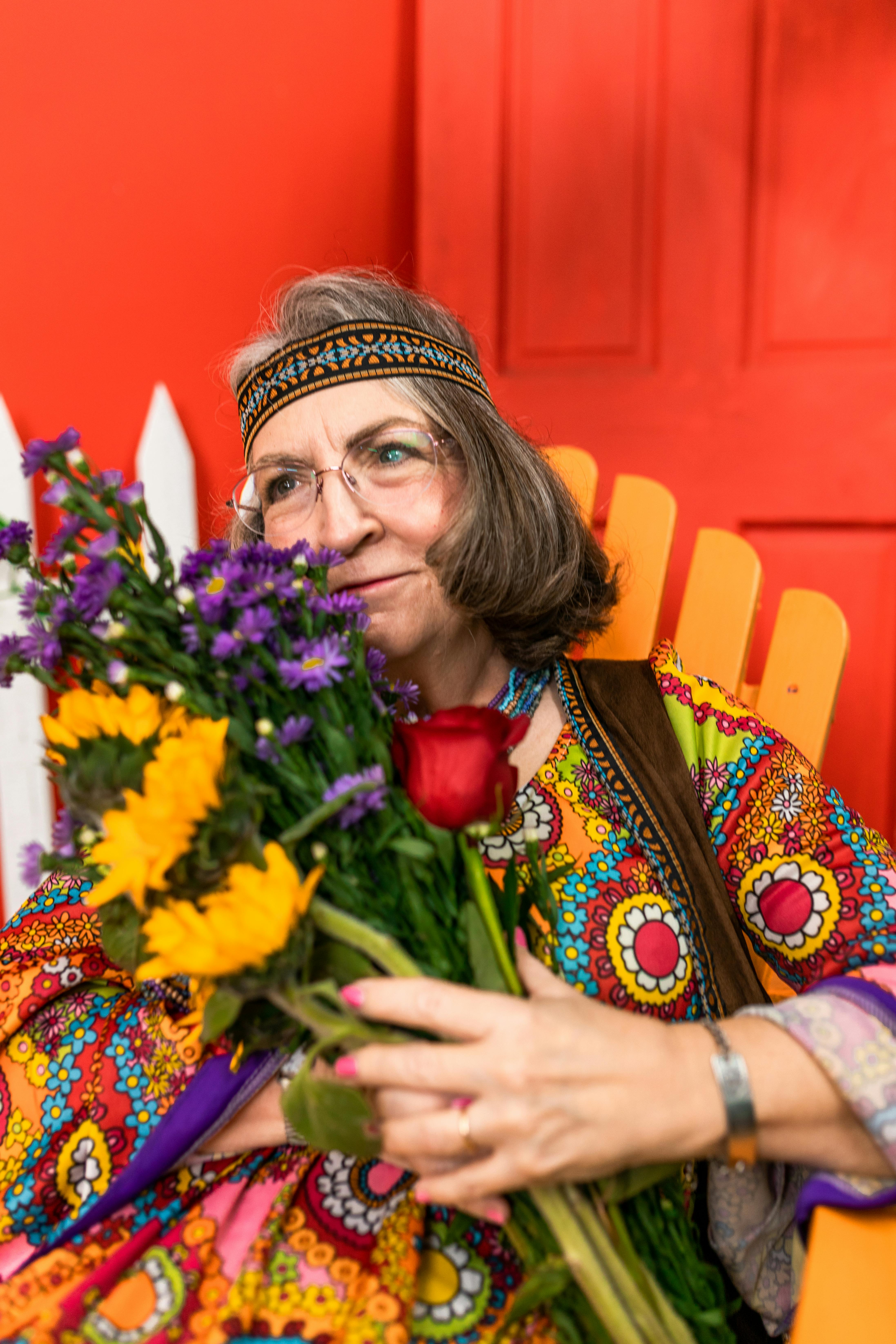 elderly woman sitting on a wooden chair with bunch of flowers