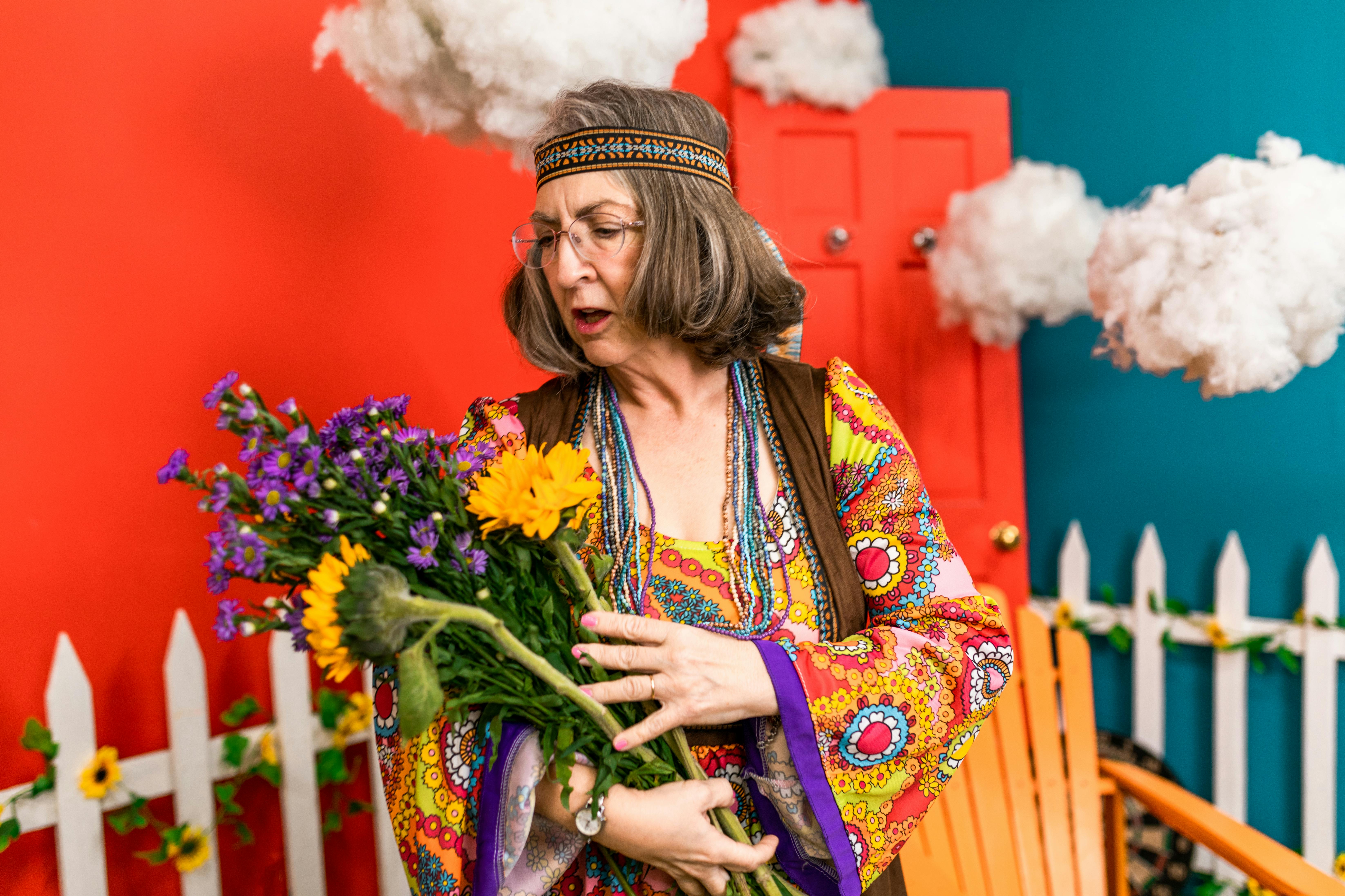 elderly woman in colorful dress shirt holding bouquet of flowers