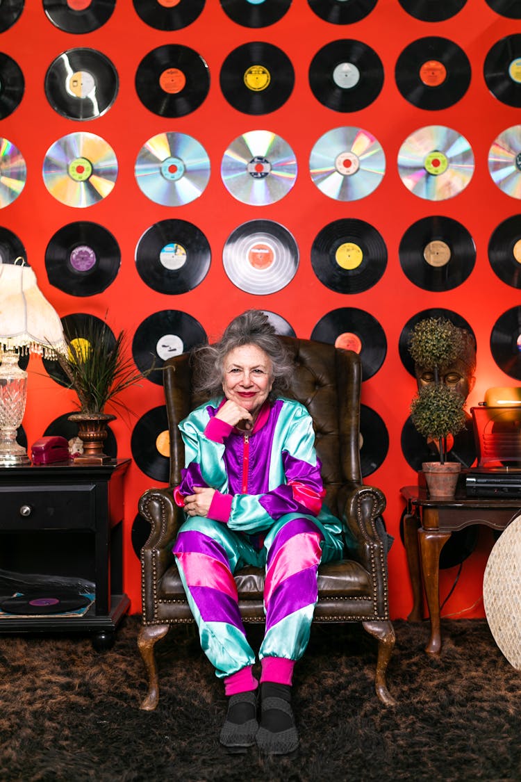 Woman In Colorful Outfit Sitting On Brown Armchair