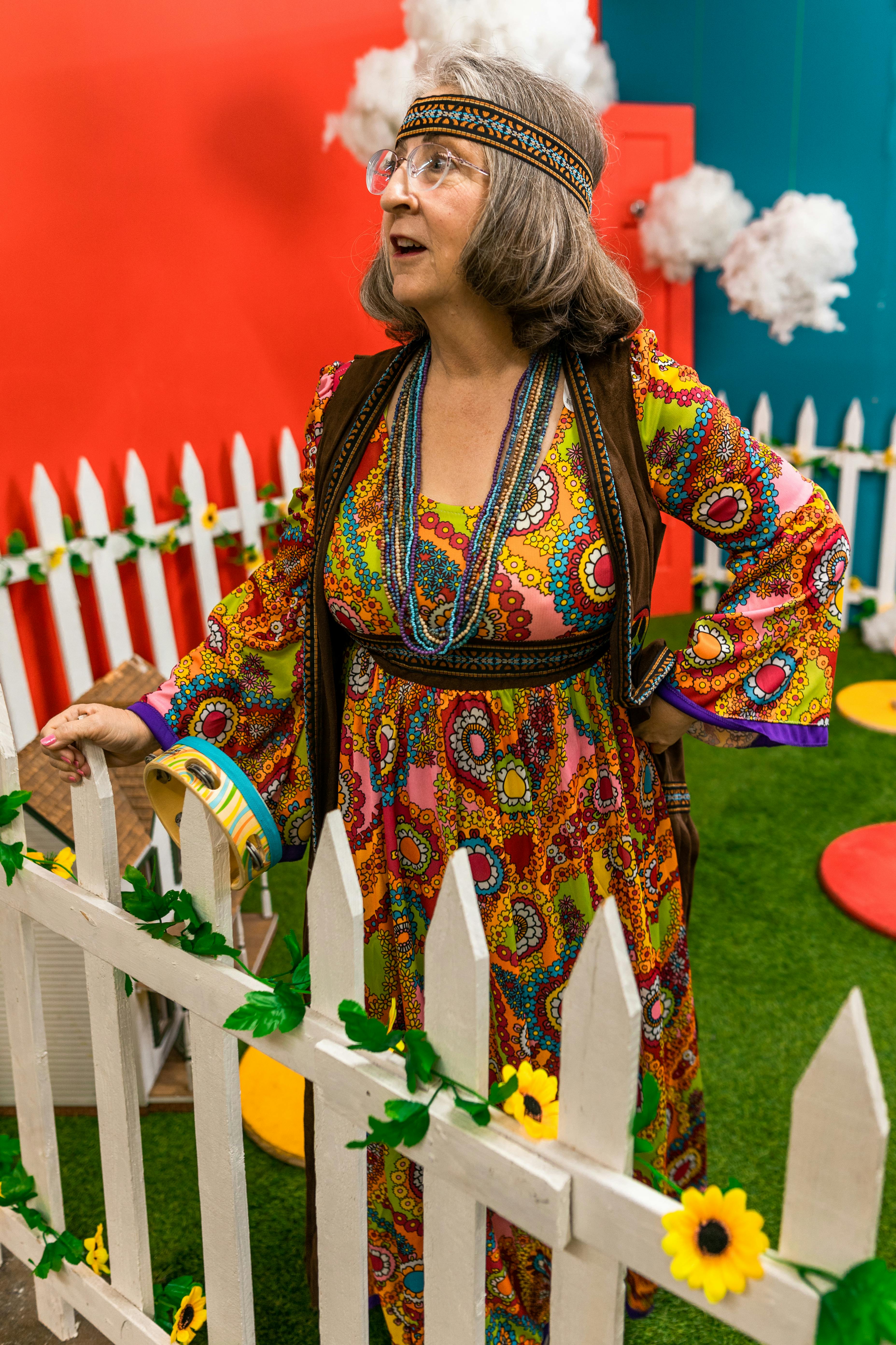 woman in a colorful dress standing near a wooden fence