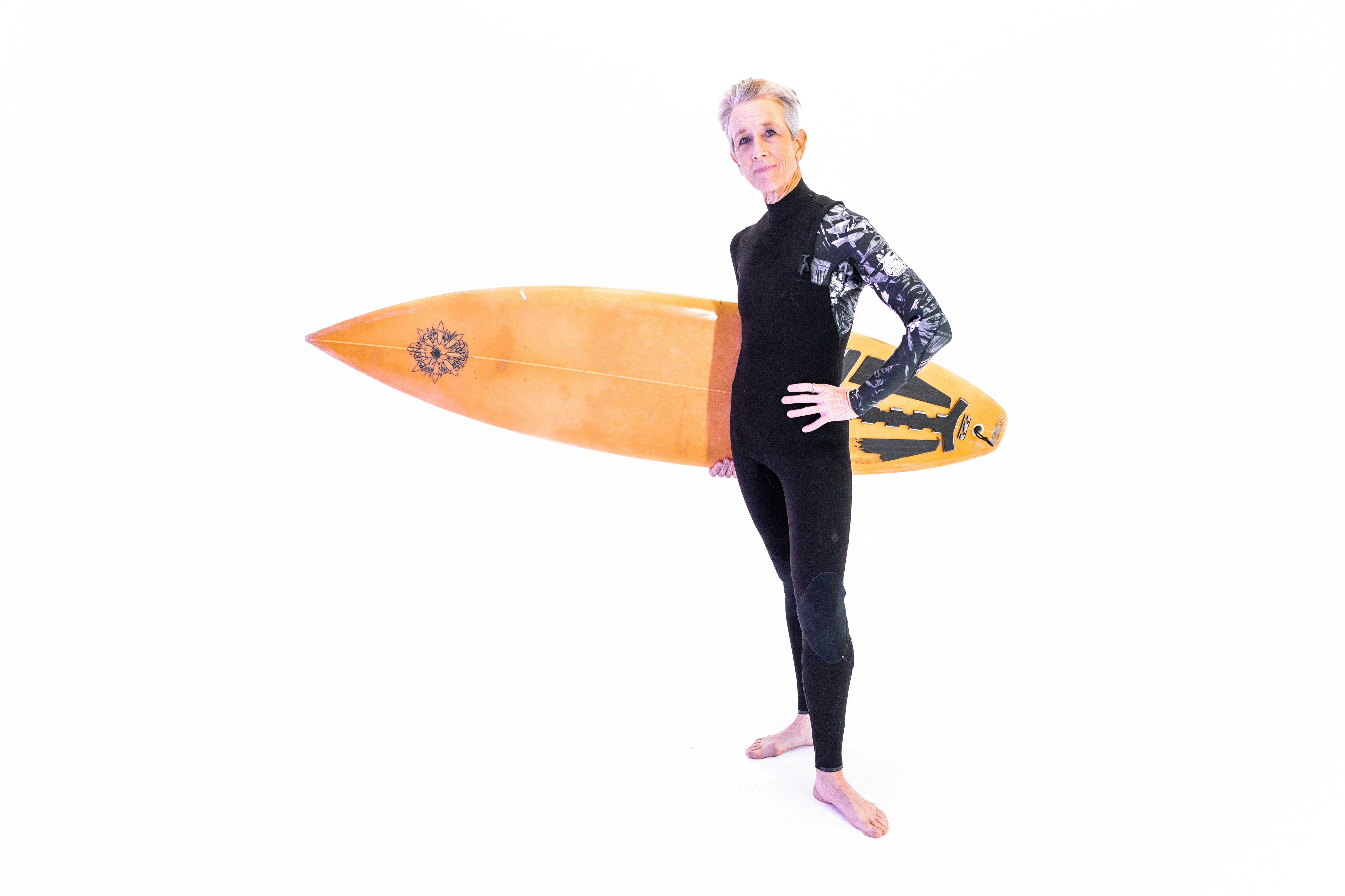 woman in black and white long sleeve shirt holding orange surfboard