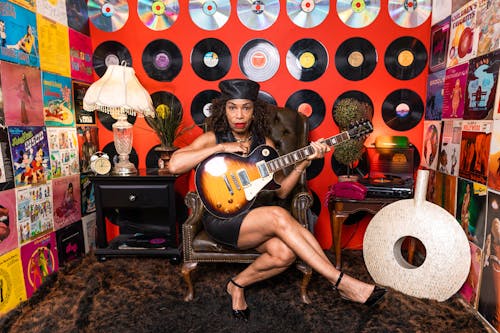 Woman Sitting On A Leather Chair Holding A Guitar