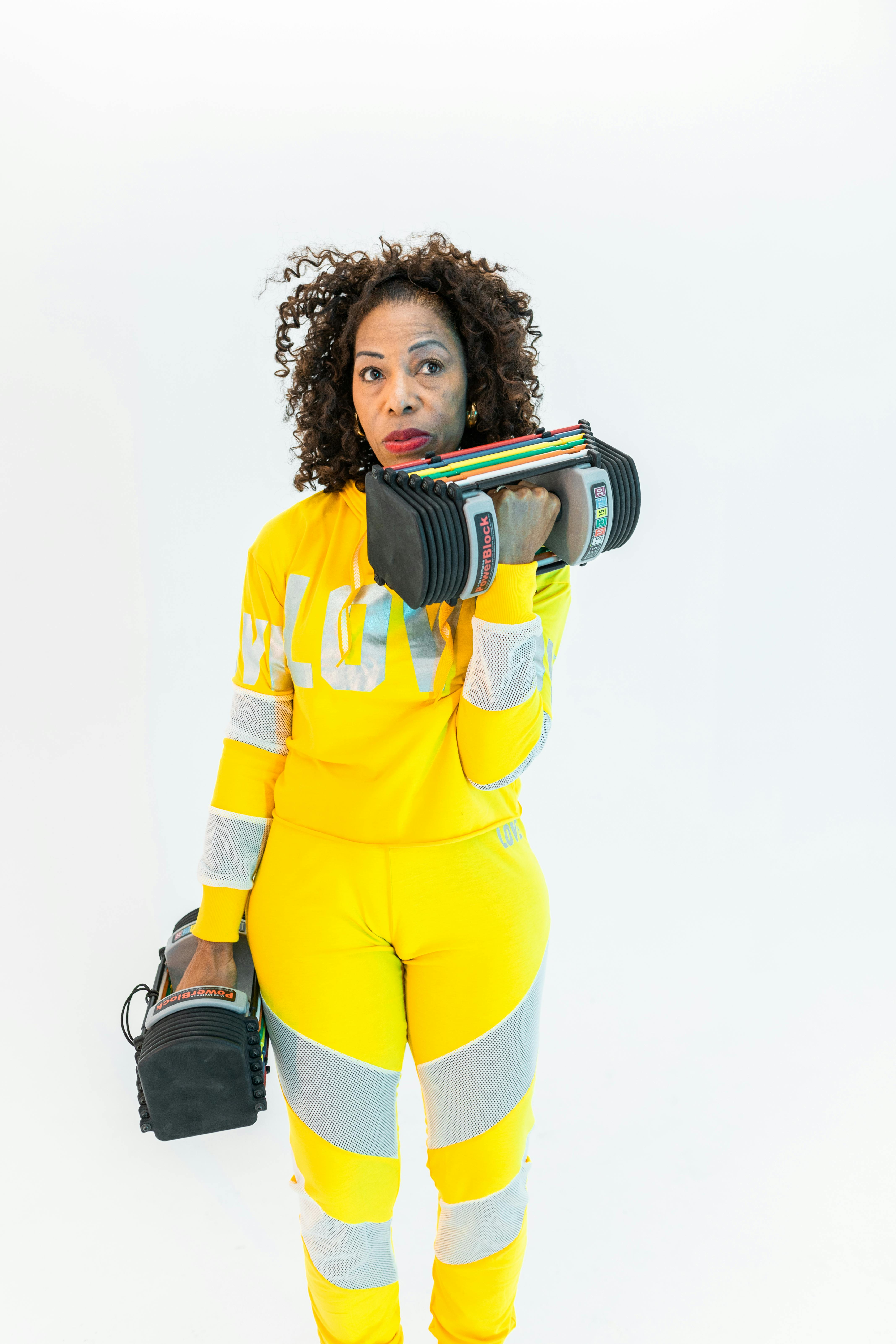 woman in yellow and gray long sleeve sportswear holding weights