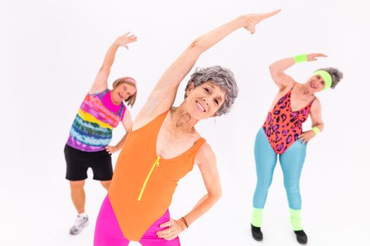 Three senior women enjoying an energetic workout session in vibrant activewear, promoting health and wellness.
