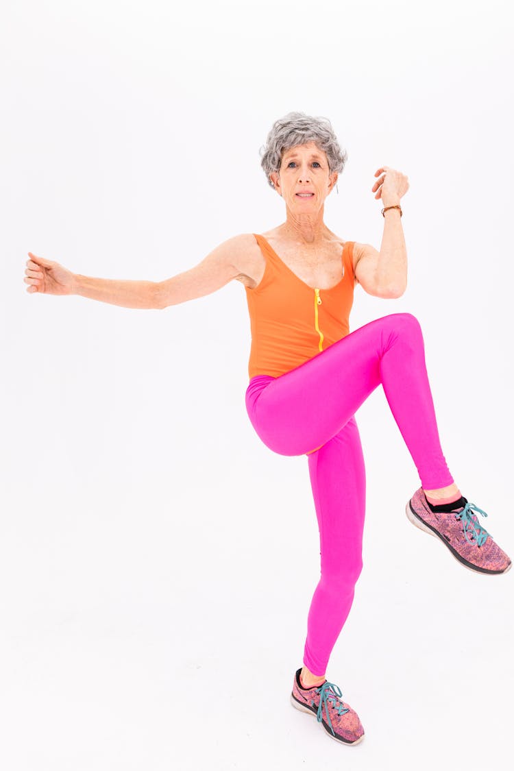 Woman In Purple Tank Top And Pink Leggings Doing Aerobics