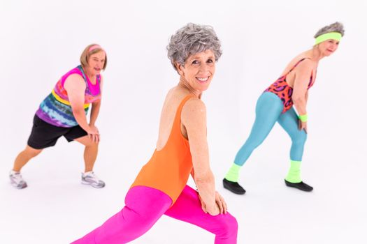 Three senior women in vibrant outfits enjoying a fun exercise session, embracing health and fitness.
