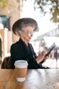 Elderly Woman Sitting By The Table With A Cup Of Coffee