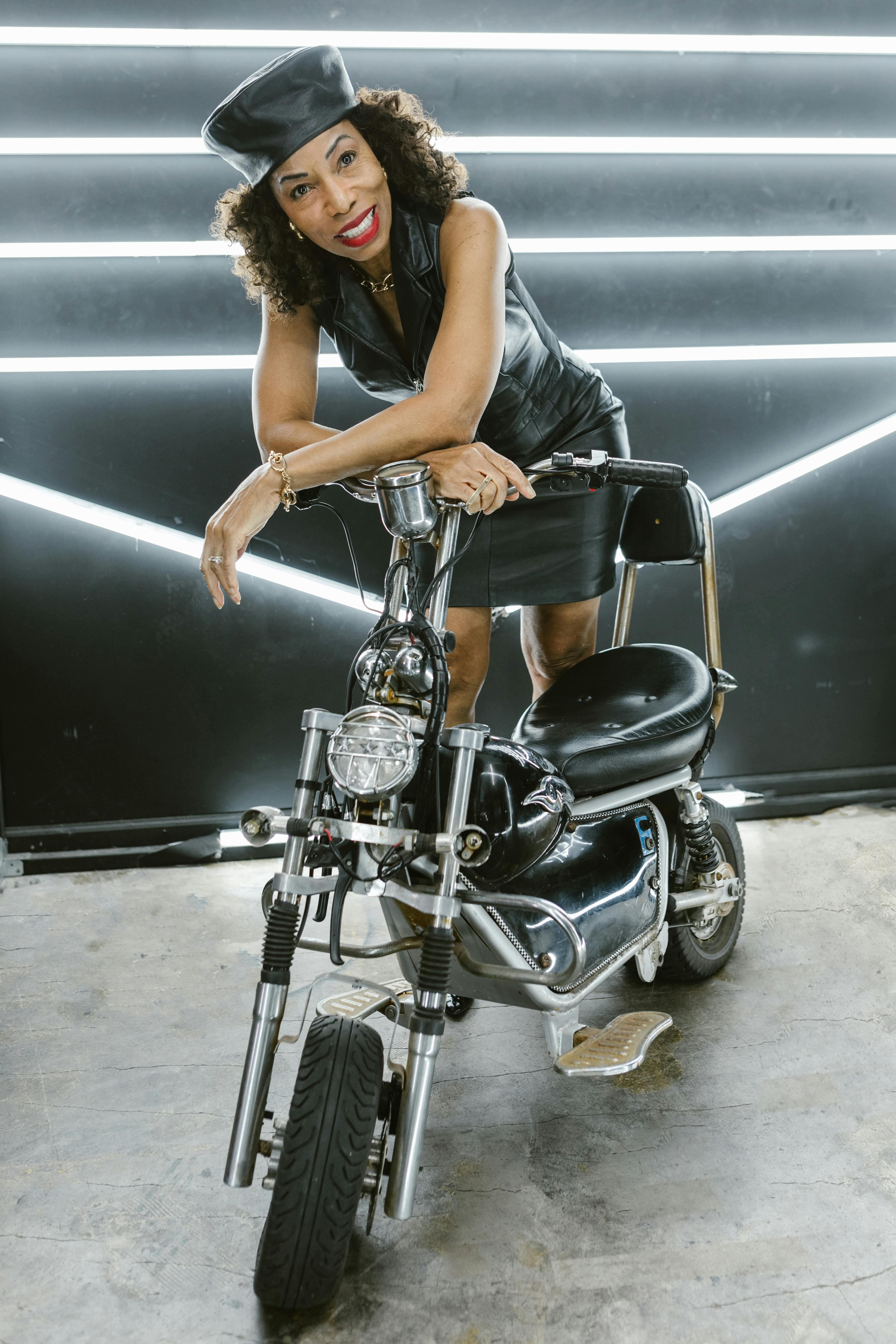 woman in black leather dress leaning on a motorbike