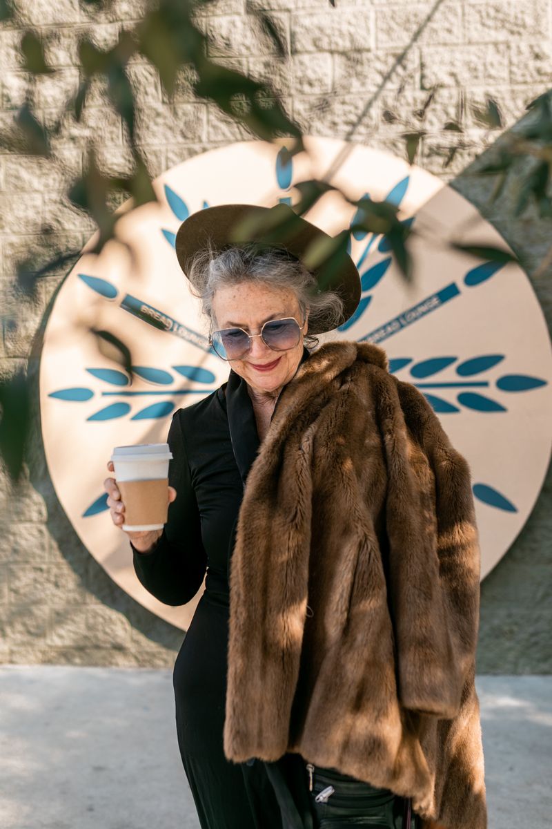 Stylish woman in fur coat enjoying coffee outside