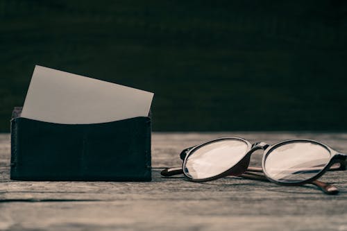 Free Close-Up Photo of a Wallet Beside Eyeglasses Stock Photo