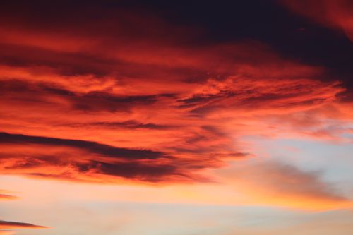 Free A stunning sunset with dramatic red and orange clouds against a light sky. Stock Photo