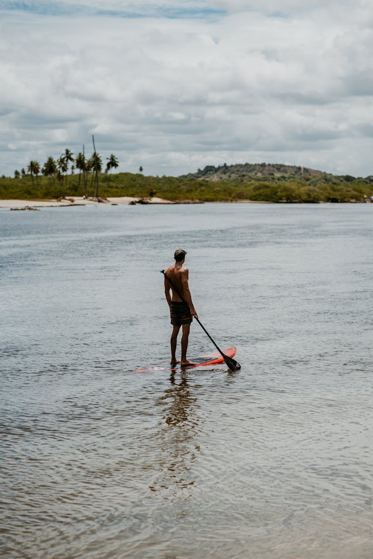 Man Standing On Paddleboard On River