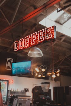 Industrial-style coffee shop with neon coffee sign and interior fixtures, creating a cozy atmosphere.